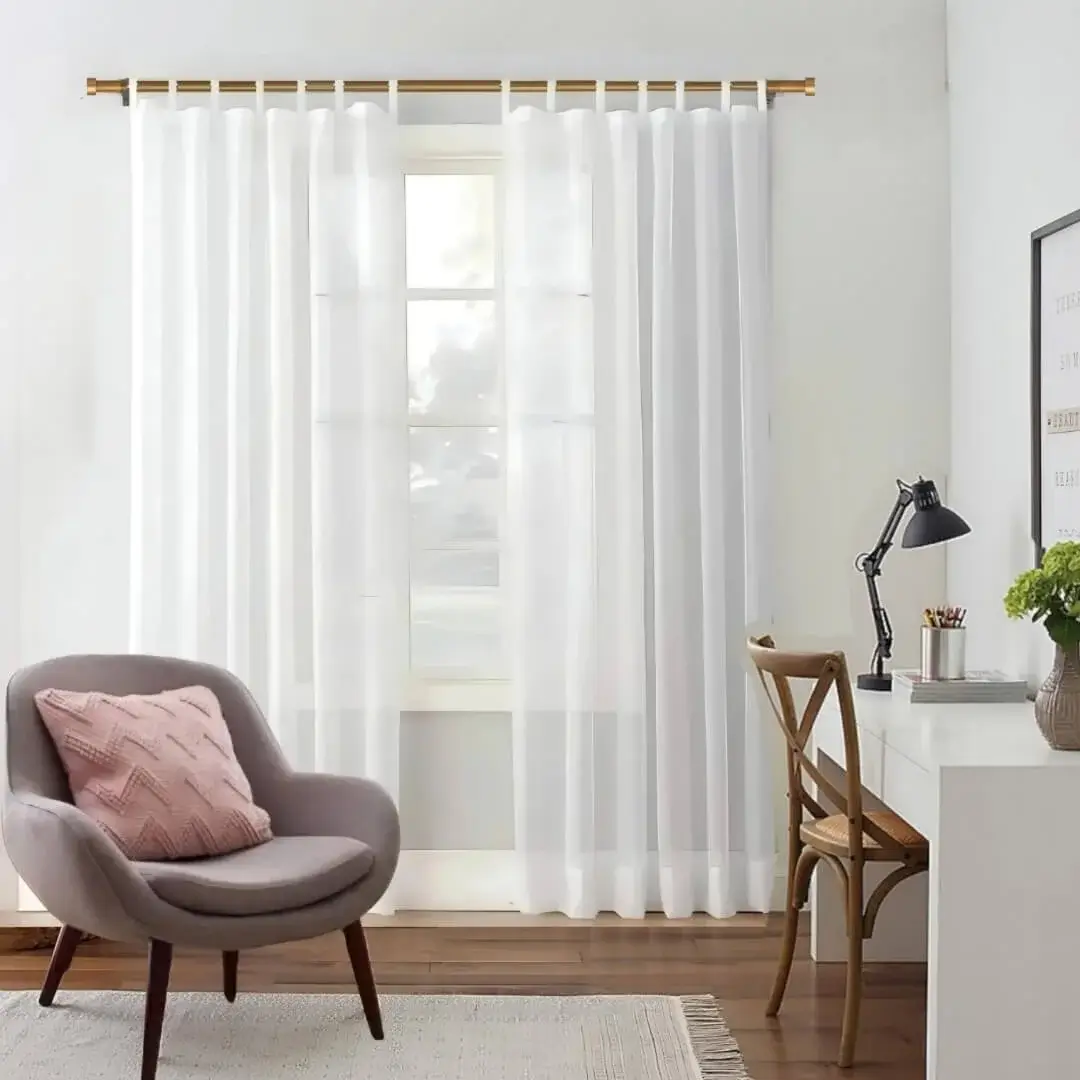 Stylish living room with flowing curtains on a gold curtain rod, paired with a single seater, and a table —creating a chic, inviting ambiance