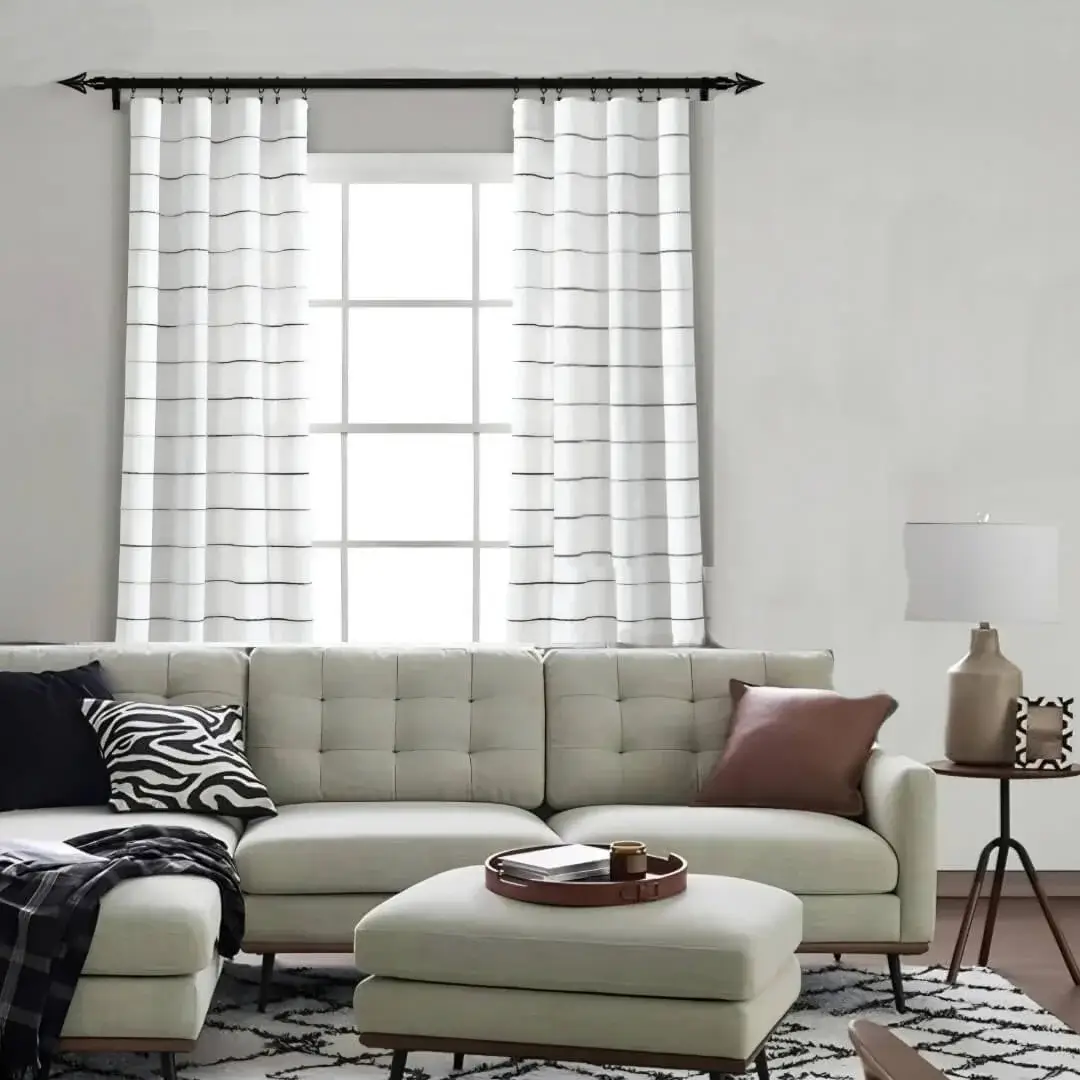 Stylish modern living room with curtains hanging from sleek black curtain rods, complemented by a cozy sofa set. Showcases functional elegance for contemporary homes