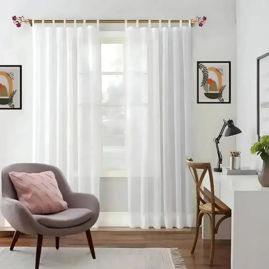 Stylish living room with flowing curtains on a gold curtain rod, paired with a single seater, and a table —creating a chic, inviting ambiance.