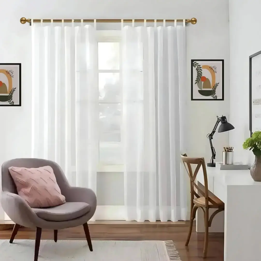 Stylish living room with flowing curtains on a gold curtain rod, paired with a single seater, and a table —creating a chic, inviting ambiance