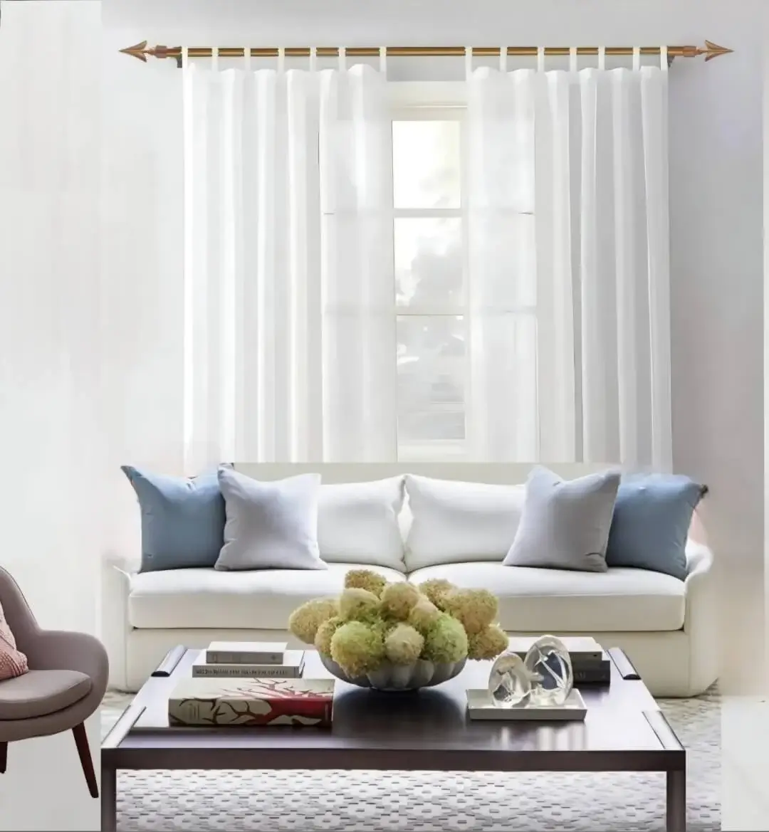 Elegant sheer curtains cascading from a luxurious gold curtain rod in a stylish living room, featuring a cozy sofa set and modern center table—creating a bright, airy, and sophisticated ambiance