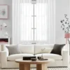 living room curtains with rods Stylish living room with flowing net curtains on a rose gold curtain rod, paired with a cozy sofa set, nice cushions, and wall paintings—creating a chic, inviting ambiance